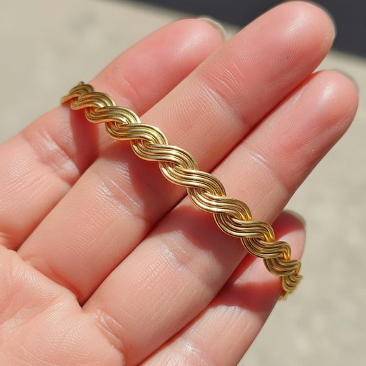 A handcrafted 14k Gold fill braided bracelet on a hand with a blurred background